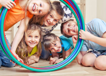 Five cheerful kids looking through hula hoops